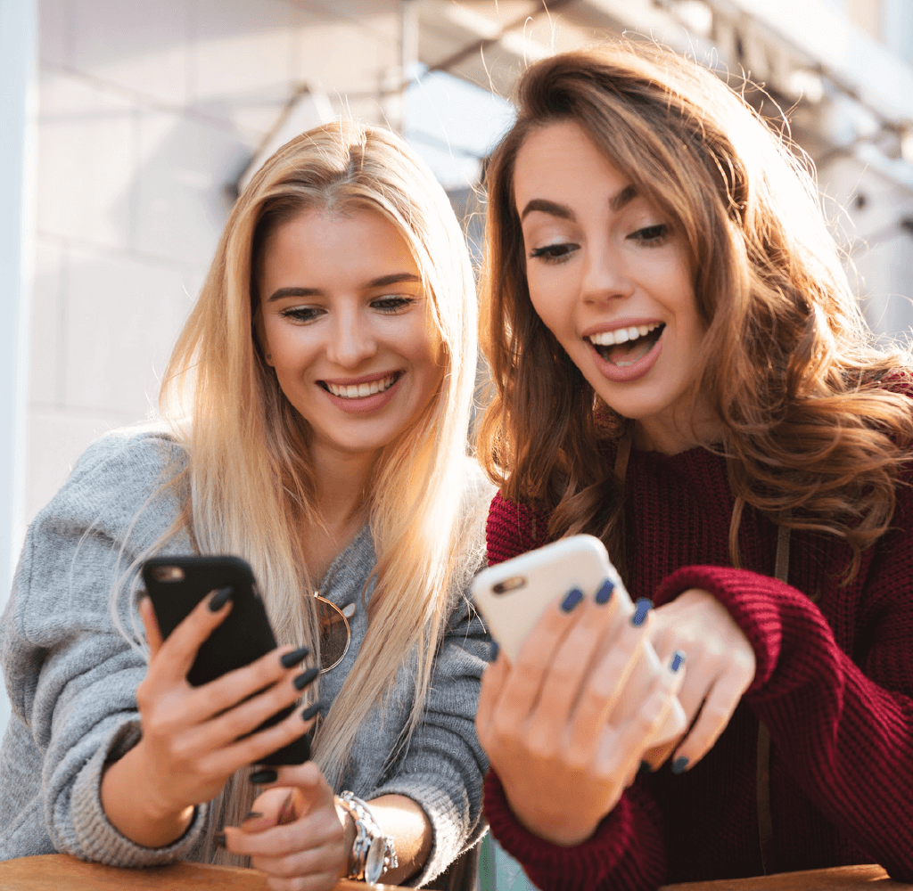 two happy young females on phones